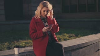 Business Woman in red coat using Mobile Phone in the sunshine city ...